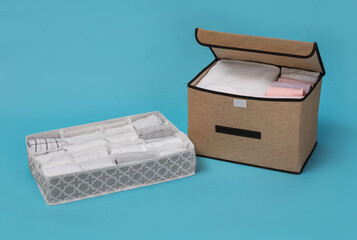Textile storage case and organizer with folded clothes on light blue background