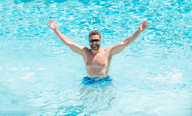 happy handsome guy in sunglasses swimming in pool on summer, pool party