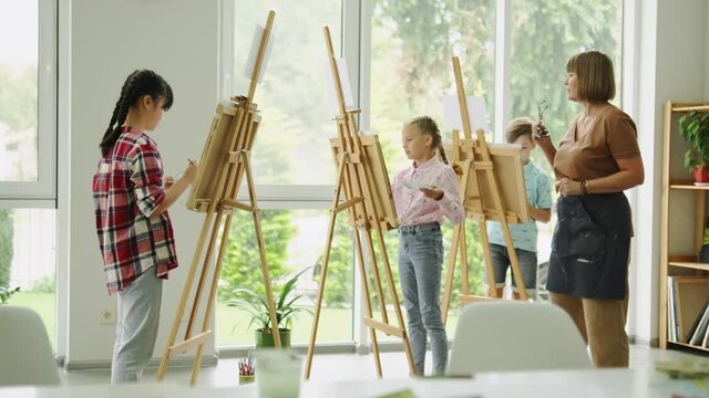 Kids painting in the modern art school with a teacher