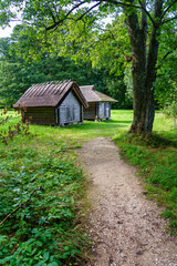 Small wooden houses in the forest with a dirt driveway.