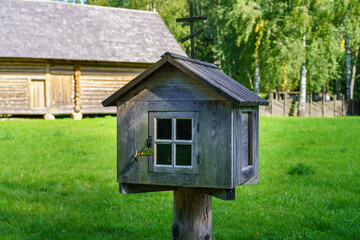 Old wooden mailbox on a post outside the house.