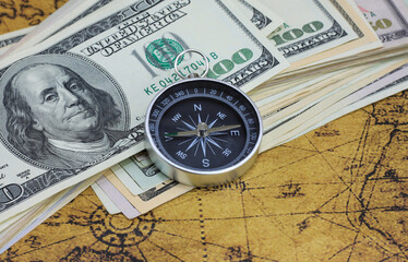Fototapeta na wymiar Classic navigation compass on background of old world map and american dollars as symbol of tourism with compass, travel with compass and outdoor activities with compass