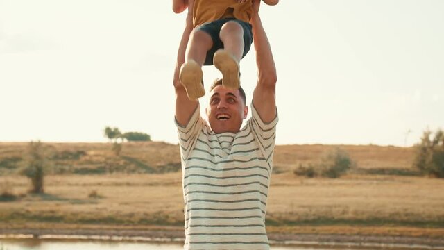 Smiling son sat on the shoulders of his positive father in nature