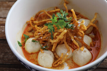 Local northern Thai food Egg noodle curry with meatballs on wood background