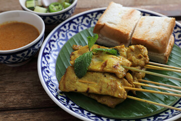 Local Thai food pork satay with oeanut dipping sauce isolated in wood background