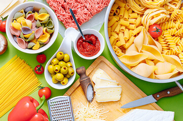 different types of italian pasta on a wooden background with various ingredients for cooking traditional italian dishes