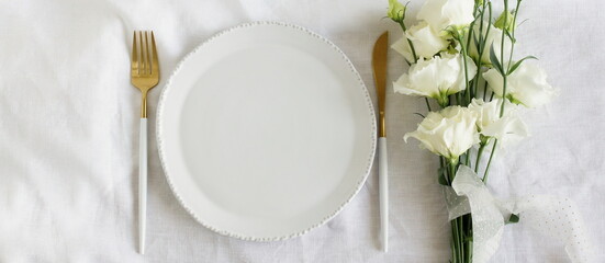 Holiday table place setting white gold   colors and white flowers bouquet top view.  Space for...