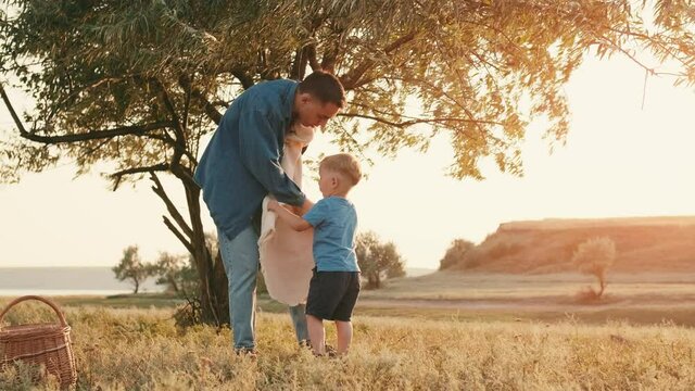Father and son spreading picnic mat in nature