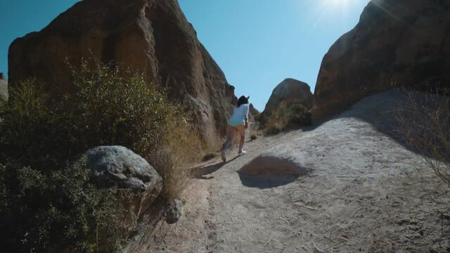 Happy raveler girl walking on top of the mountain. Devrent Valley Imaginary Valley full of unique rose rock formations in Cappadocia, Turkey. Travel and vacation concept.