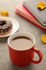 Coffee cup, donut and autumn leaves on grey background. Autumn concept. Vertical photo