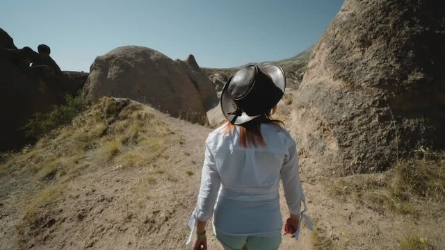 Happy raveler girl walking on top of the mountain. Devrent Valley Imaginary Valley full of unique rose rock formations in Cappadocia, Turkey. Travel and vacation concept.