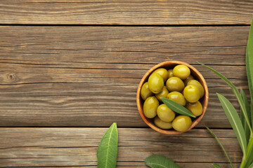Fresh olives in bowl with leaves on grey background with copy space.
