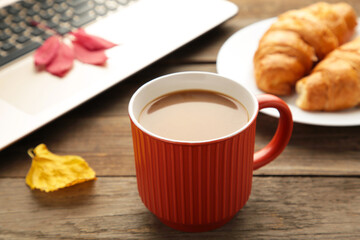 Hot coffee with croissant and autumn leaves on grey - seasonal relax concept.
