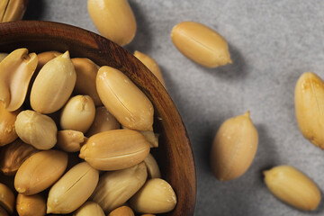 Peanuts in wooden bamboo bowl on concrete background. Nuts.