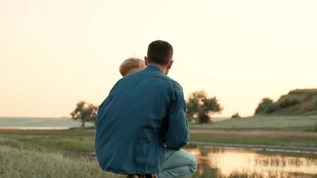 Back view of father with his son pointing finger forward in nature