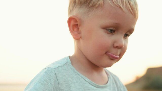 Close-up view of a little boy biting his lips in nature