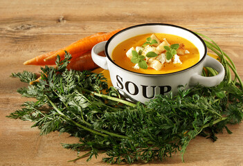  carrot puree soup with croutons, cheese and oregano in a bowl on a wooden background and fresh...