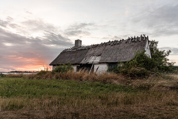 an old abandoned house with a thatched roof, solitary located overlooking the sea at Bisserup