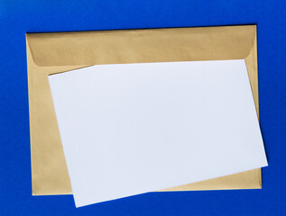 blank sheet of paper and craft envelope on blue background