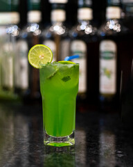 Green cocktail with lime and ice and blue straw