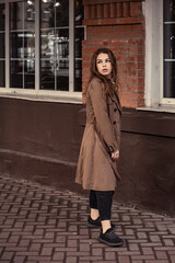 Fototapeta premium Young woman walking on the street city wall background in brown coal and black shoes. Autumn season