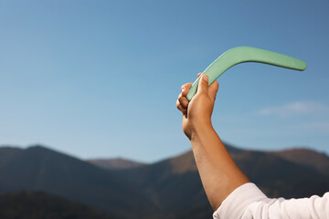 Man throwing boomerang in mountains, closeup. Space for text - obrazy, fototapety, plakaty