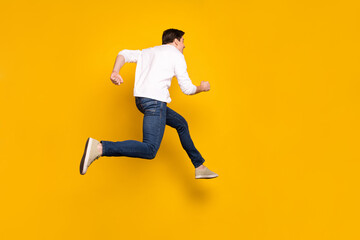 Fototapeta na wymiar Full length body size photo man jumping up running fast in casual clothes isolated vivid yellow color background