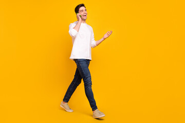 Photo portrait young man talking on mobile phone smiling wearing jeans isolated bright yellow color background