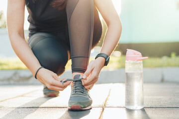 Girl in sportswear tying laces on sneakers