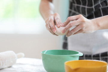 close up chef hands cracking fresh egg yolk and dropping in a bowl