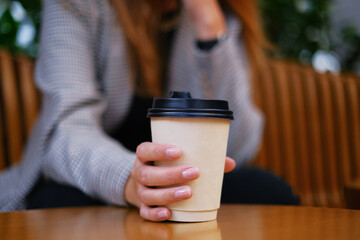 beautiful woman holding coffee in a paper cup. coffee to go. girl drinking tea on the terrace