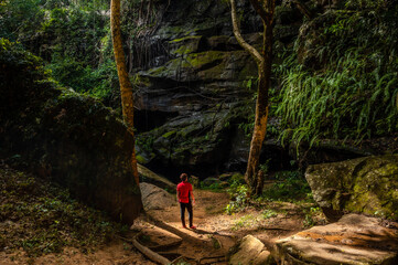 Tourists stand in front of a large rock on the tropical forest at Tat Fa Waterfall, the best waterfall within Phu Wiang National Park, Khon Kaen, Thailand.