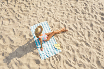 Woman sunbathing on beach towel at sandy coast, aerial view