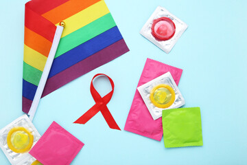 Condom in packs with red ribbon and lgbt flag on blue background