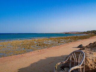 Beautiful seascape at sunset. Old rattan chair on the wild beach