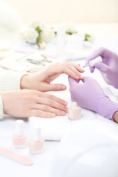 Manicurist in gloves making manicure for client in salon
