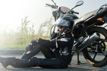 Woman biker in leather pants, motorcycle safety helmet sits next to her motorcycle. Space for text, copy-space.