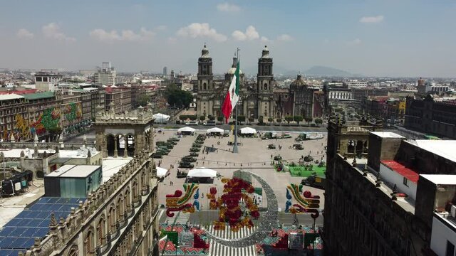 Aerial view of the iconic giant Mexican flag in Zocalo square, downtown Mexico City, Mexico, backgrounded by the Metropolitan Cathedral.