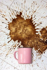A pink ceramic mug, cup fell on a white wooden parquet floor and left a big stain on it. Spilled coffee in the morning. Lots of hot coffee drink brown splashes flying in different directions flatly.