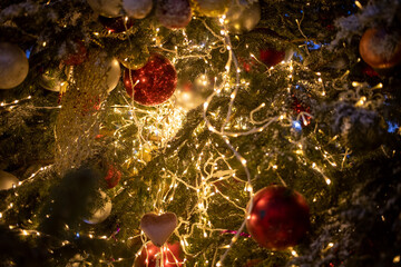 Fototapeta na wymiar texture new year. Close-up of a Christmas tree branch with decorative balls, toys and a shining garland. soft focus, background in blur.