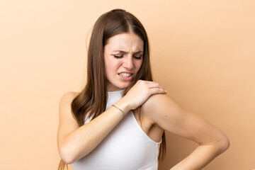 Young caucasian woman isolated on beige background suffering from pain in shoulder for having made an effort