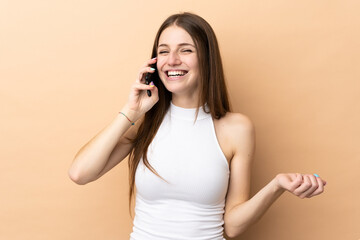 Fototapeta premium Young caucasian woman isolated on beige background keeping a conversation with the mobile phone with someone