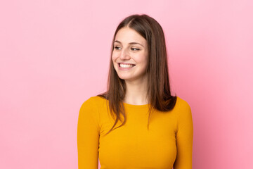 Obraz premium Young caucasian woman isolated on pink background looking to the side and smiling