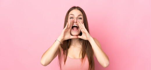Young caucasian woman isolated on pink background shouting and announcing something