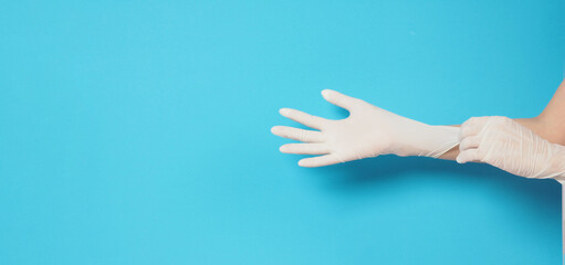Two hand is wearing white surgical gloves or latex gloves on a blue background.
