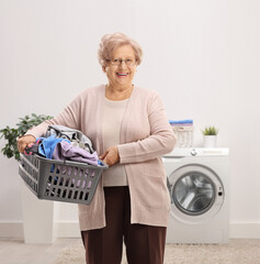 Elderly woman holding a laundry basket with clothes