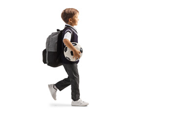 Full length profile shot of a schoolboy carrying a football and walking