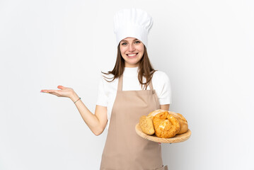 Young woman in chef uniform isolated on white background extending hands to the side for inviting to come