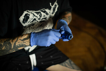Man's hand holding tattoo machine. Master of tattoo process holds an induction machine for drawing...