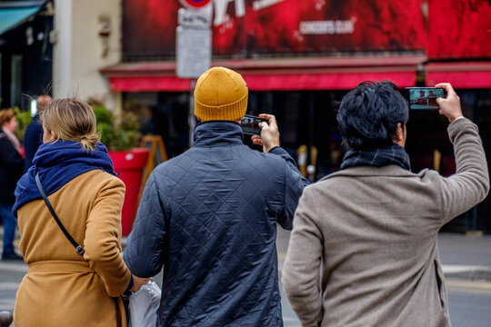 Tourists photographing the Moulin Rouge on mobile phones, Boulevard de Clichy, Paris, France